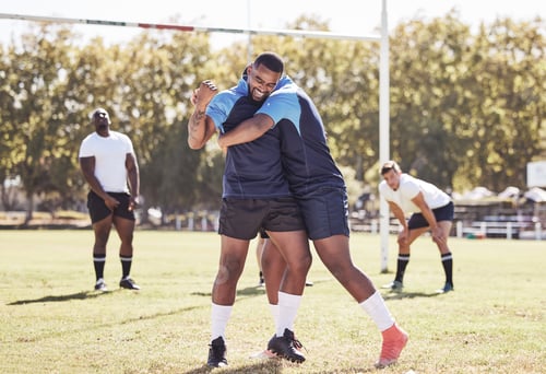 Preview: Two african american rugby teammates celebrating scoring a try or winning a match outside on a spor