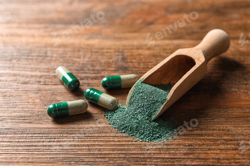Preview: Scoop of spirulina powder and pills on wooden table