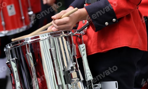 Preview: Closeup of a musician playing a drum wearing a bright red coat