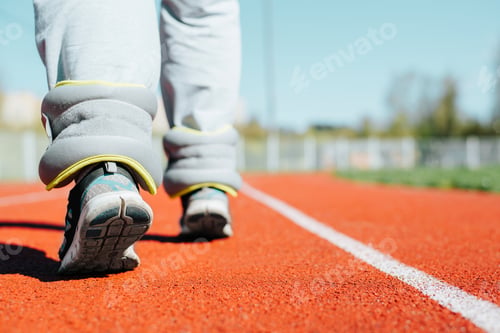 Preview: Woman with fitness weights for jogging and weight loss training walking along track in outdoor
