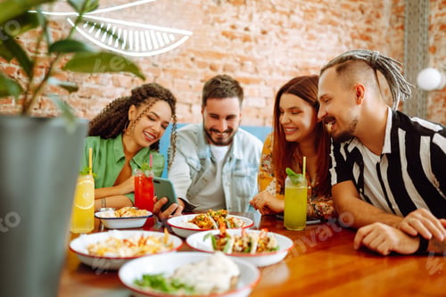 Preview: Happy friends having a great time in cafe. Young people sitting in a restorane having fun together