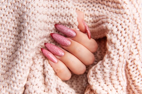 Preview: Hand with pink manicure nails on knitted sweater