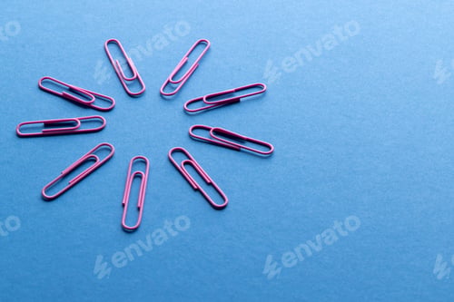 Preview: Close up of pink paper clips in circle and copy space on blue background
