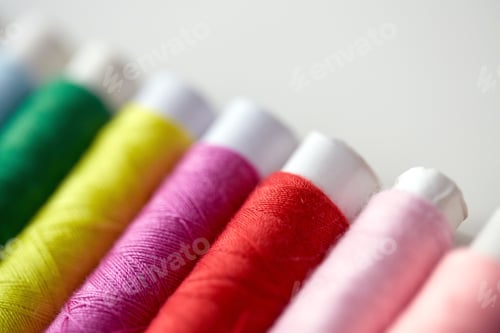 Preview: row of colorful thread spools on table