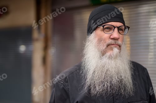 Preview: Face of mature handsome bearded man thinking in the streets outdoors