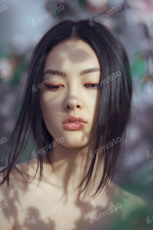 Preview: Beautiful girl standing at blossoming tree in the garden
