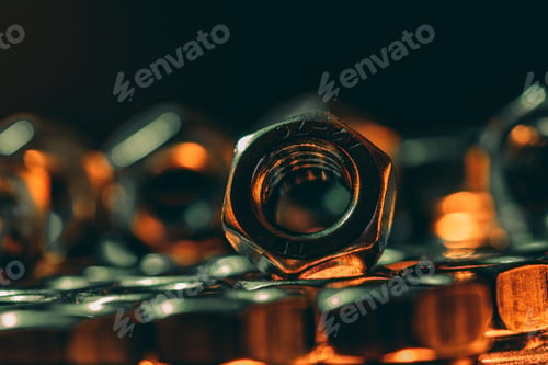 Preview: Selective focus shot of metal screw nuts placed on each other on a dark background