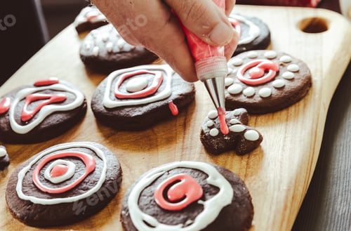 Preview: Man’s hand piping icing on gingerbread cookies