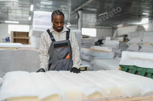 Preview: African american Furniture maker inspecting foam mattress in factory warehouse