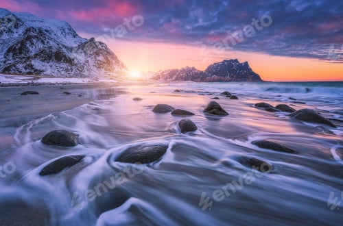 Preview: Amazing sandy beach with stones in blurred water at sunset