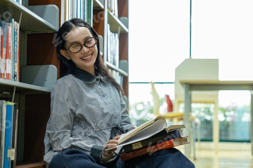 Preview: Woman Reading on the Library Floor Between Bookshelves