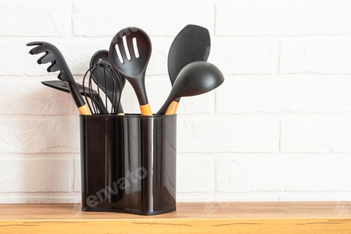 Preview: Kitchen utensils in container near white wall.