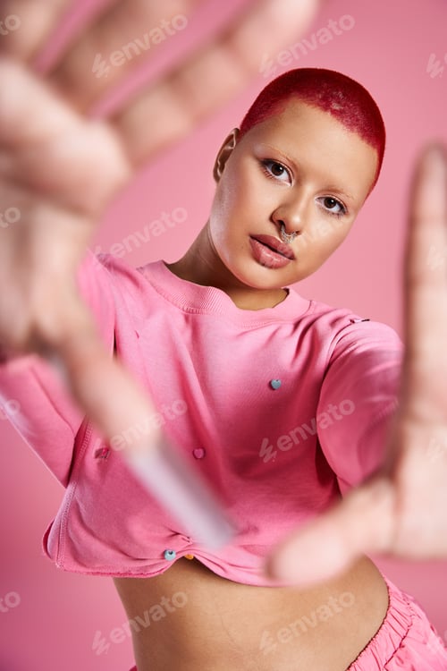 Preview: A young woman embraces her bold style with pink hair in a vibrant studio setting