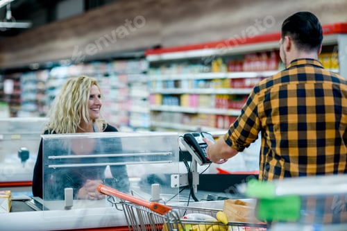 Preview: Man making a contactless payment with his smartphone at a supermarket