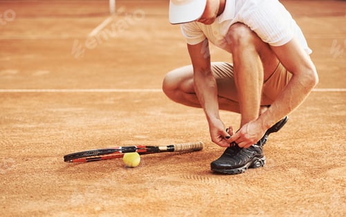 Preview: Getting prepared. Young tennis player in sportive clothes is on the court outdoors