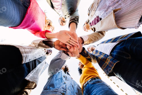 Preview: United young group of diverse people joining hands outdoors