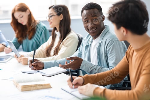 Preview: International group of people sitting at desk and talking
