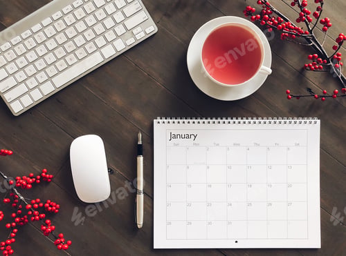 Preview: Top view of a desk with a January calendar, tea, keyboard and red winterberries