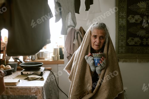 Preview: Senior Caucasian Woman Sitting Indoors Holding Mug and Looking Thoughtful