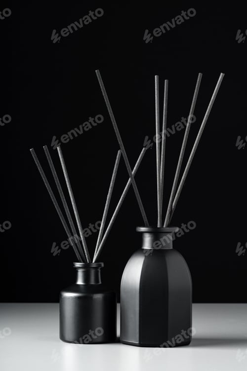 Preview: Two Black Reed Diffuser Bottles on White Surface Against Black Background