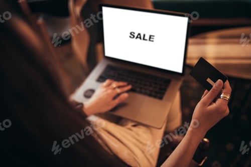 Preview: Young woman shopping online using her credit card and laptop sitting in a coffeehouse.