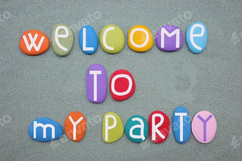 Preview: Welcome to my party, creative message composed with multi colored stone letters over green sand