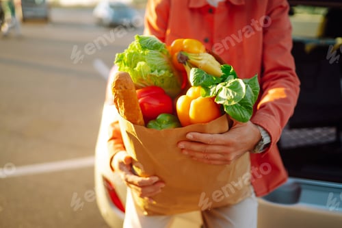 Preview: Young man with shopping bag full of vegetables near the car. Healthy lifestyle.