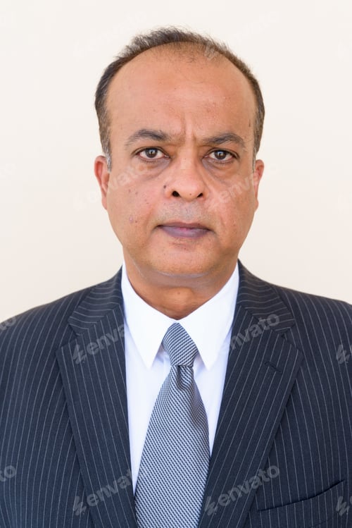 Preview: Portrait of Indian businessman against plain wall outdoors