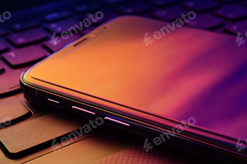 Illuminated Smartphone Lying on Keyboard at Night