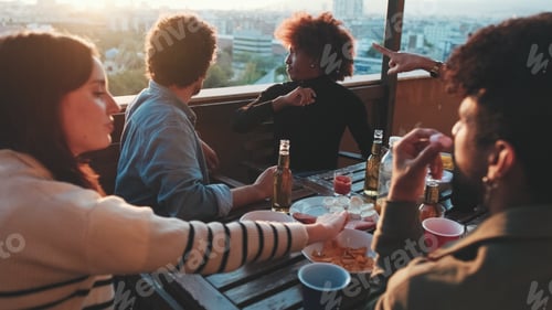 Preview: Guys and girls at party on the terrace eat and drink, have fun and joke around the table