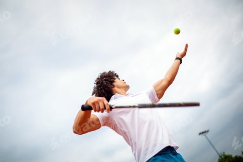 Preview: Young handsome tennis player with racket and ball prepares to serve at beginning of game or match