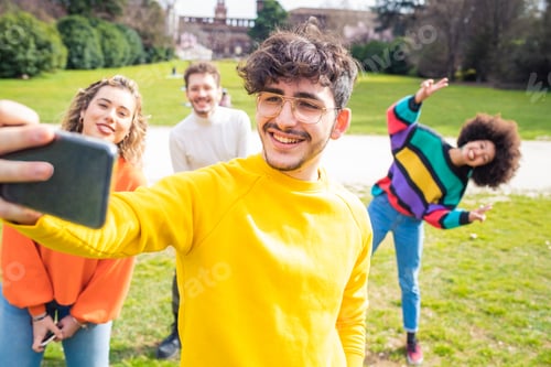 Preview: Four people multiethnic friends having fun outdoor using smartphone taking selfie