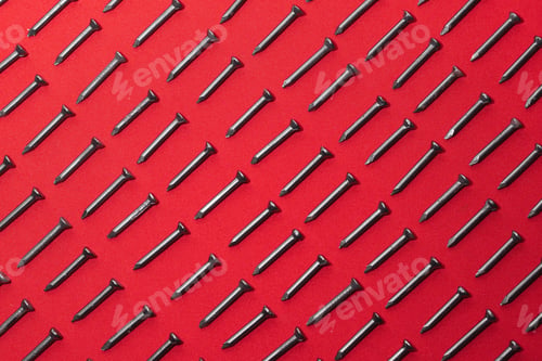 Preview: lot of black steel nails, on red background, arranged diagonally perfectly