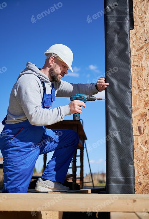 Preview: Builder installing corrugated iron sheet used as facade of future wooden frame house.
