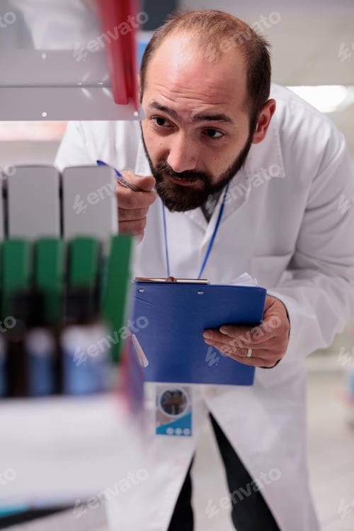 Preview: Caucasian pharmacist looking at drugs packages checking bar code during store inventory