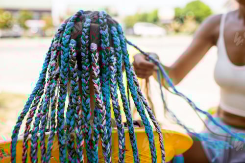 Preview: A girl in a suit weaves African braids in her hair on a sunny day