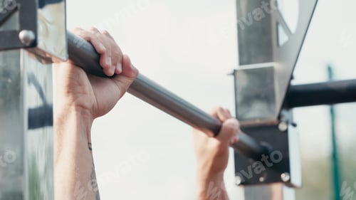 Preview: cropped view of sportsman working out on horizontal bar outdoors