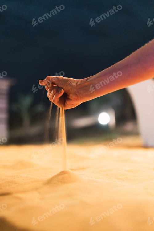 Preview: Crop hand spilling dry sand