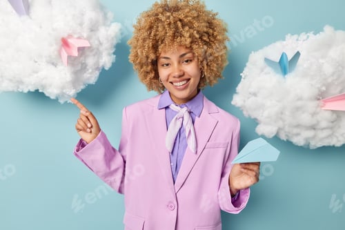 Preview: Waist up shot of pretty curly haired woman wears formal purple jacket points index finger on white c