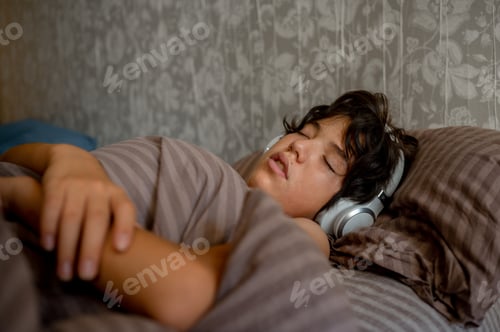 Preview: teenage boy sleeps at home on the couch listening to music with headphones