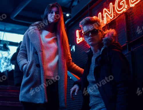 Preview: Young stylish couple wearing warm clothes standing on the staircase to the underground nightclub