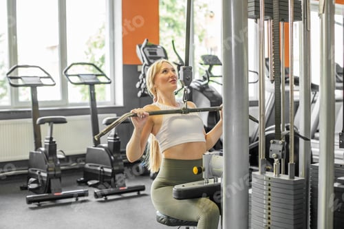 Preview: Focused woman doing lat pulldown workout in gym
