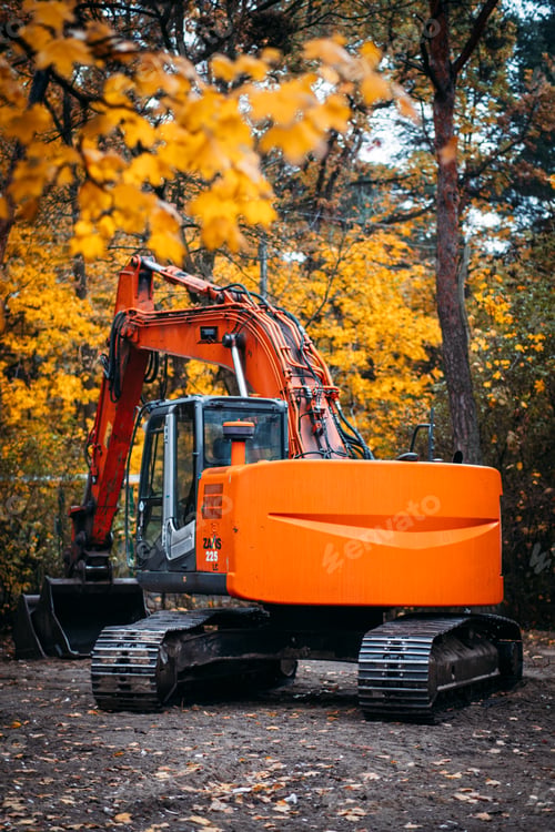 Preview: A bright orange excavator stands idle in a forest clearing surrounded by vivid fall foliage