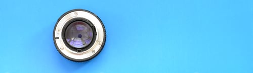 Preview: One photographic lense lie on a bright blue background. Space for text