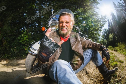 Preview: Male biker sitting on dirt road near motorcycle