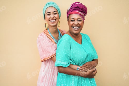 Preview: Happy african mother and daughter hugging each other while wearing traditional dresses