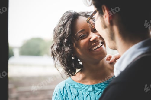 Preview: multiethnic couple of lover having fun and hugging indoor in their house