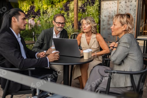 Preview: Business team collaborating on laptop at outdoor cafe