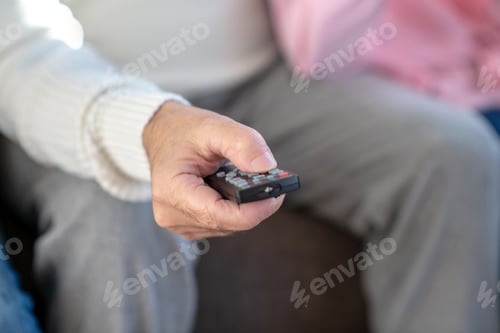 Preview: Close up picture of a man sitting on the sofa with a remote control in his hand