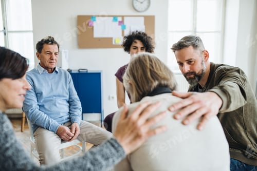 Preview: Men and women sitting in a circle during group therapy, supporting each other.